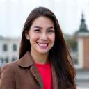 A young professional woman smiling in front of a landmark in Vienna.