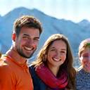 A happy family of four posing for a photo against an alpine backdrop.